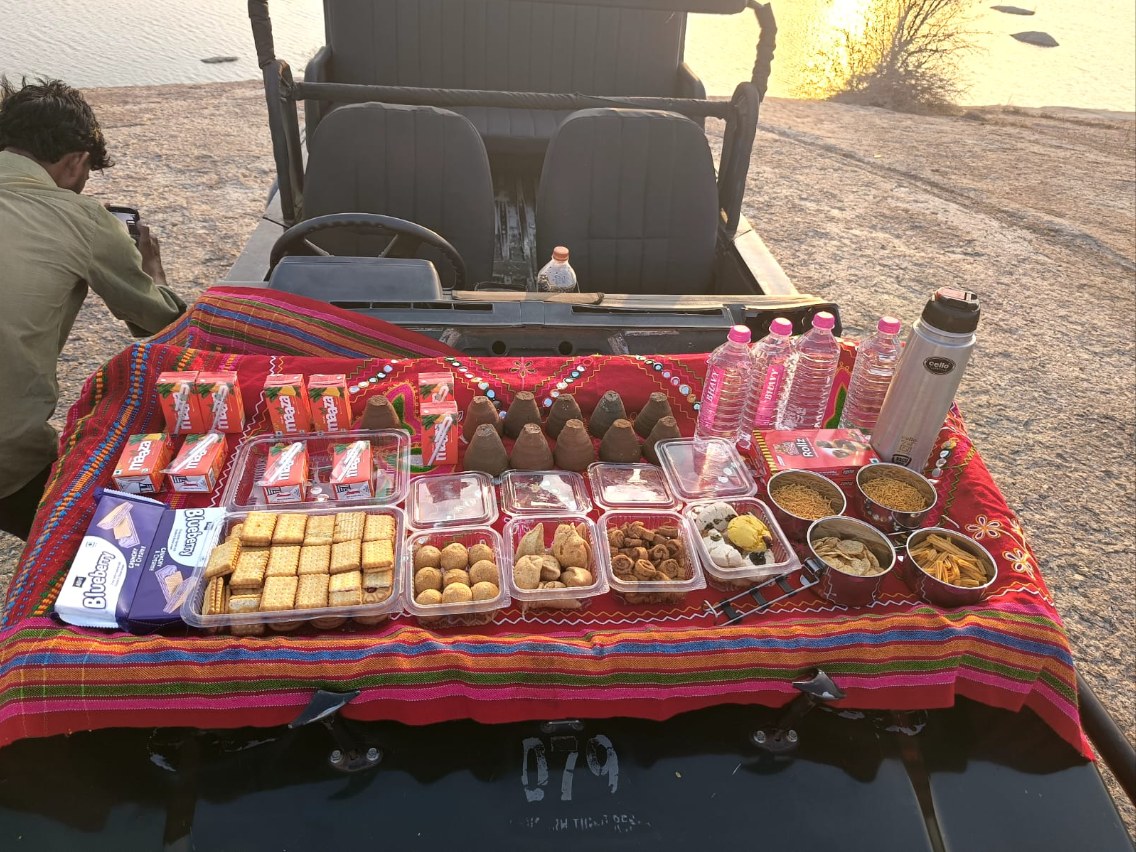 Guests pouring hot chai beside the safari jeep at sunrise